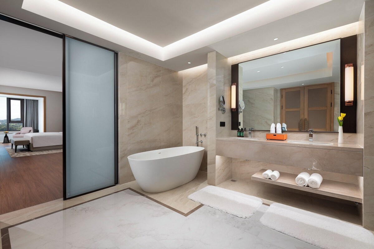 Ein modernes Badezimmer mit einer freistehenden Badewanne, einem großen Spiegel und einem Waschtisch mit Regalen.