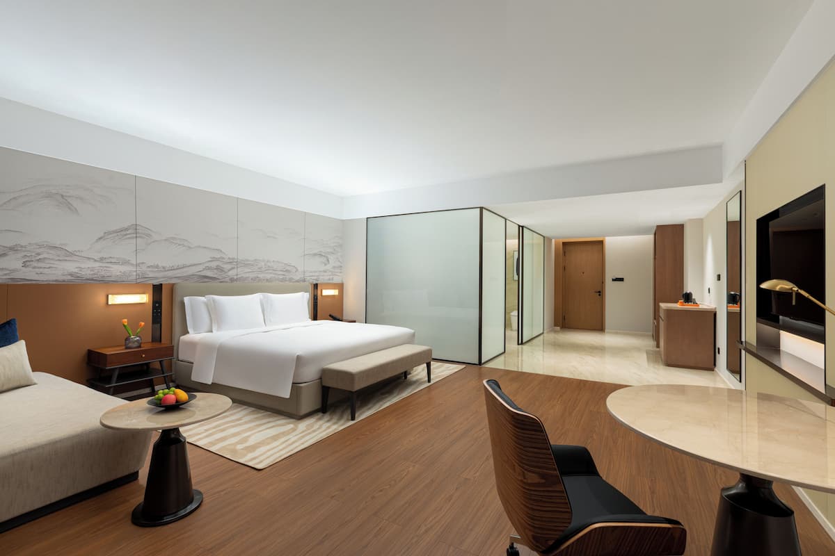 Une chambre d’hôtel moderne équipée d’un lit, d’une table de chevet, d’une chaise et d’un téléviseur à écran plat.