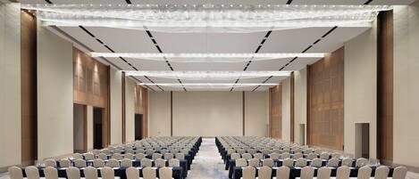 A conference room with rows of tables and chairs, a patterned carpet, and a modern ceiling design.