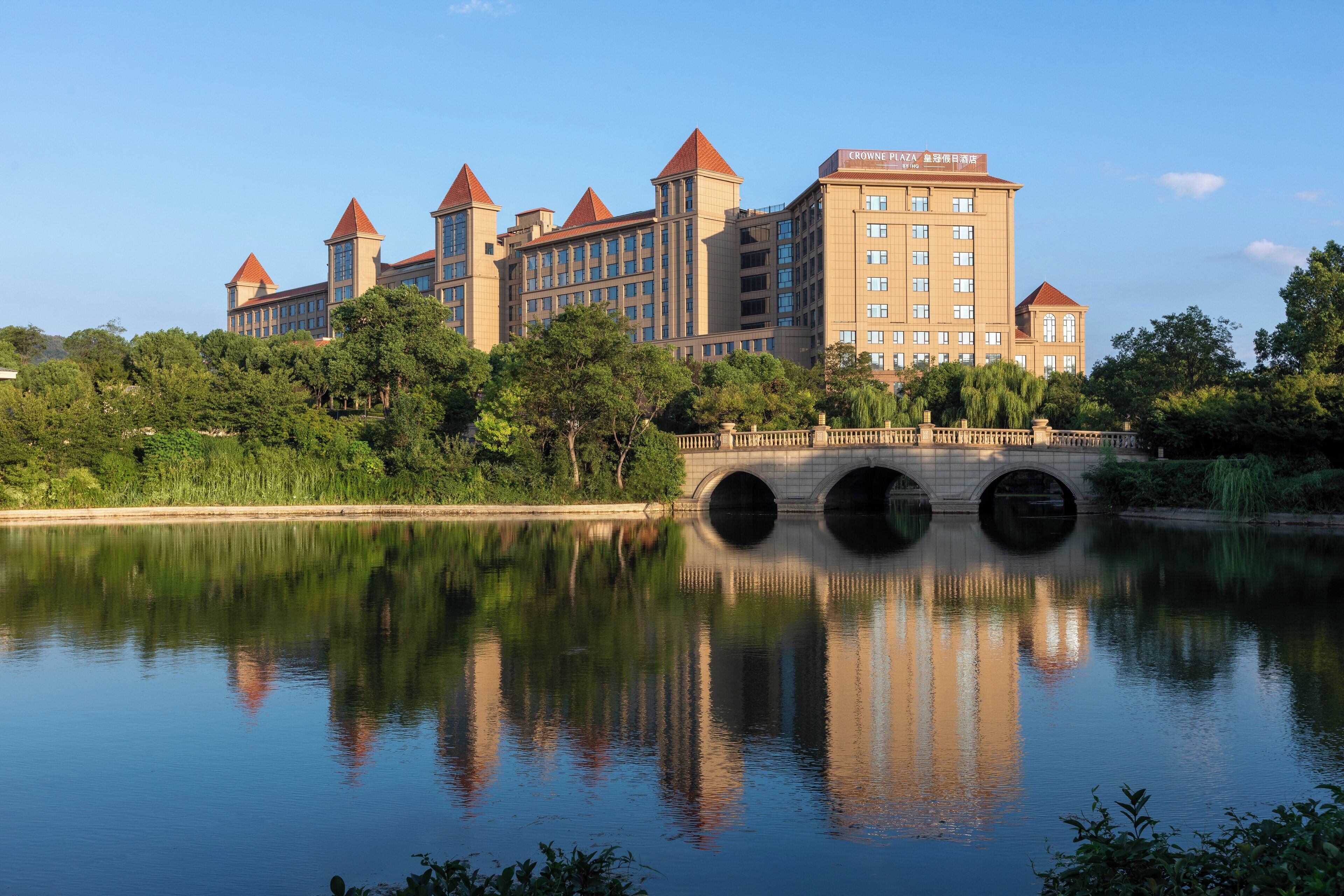 Un gran hotel con múltiples torres y un puente sobre una superficie acuática tranquila.