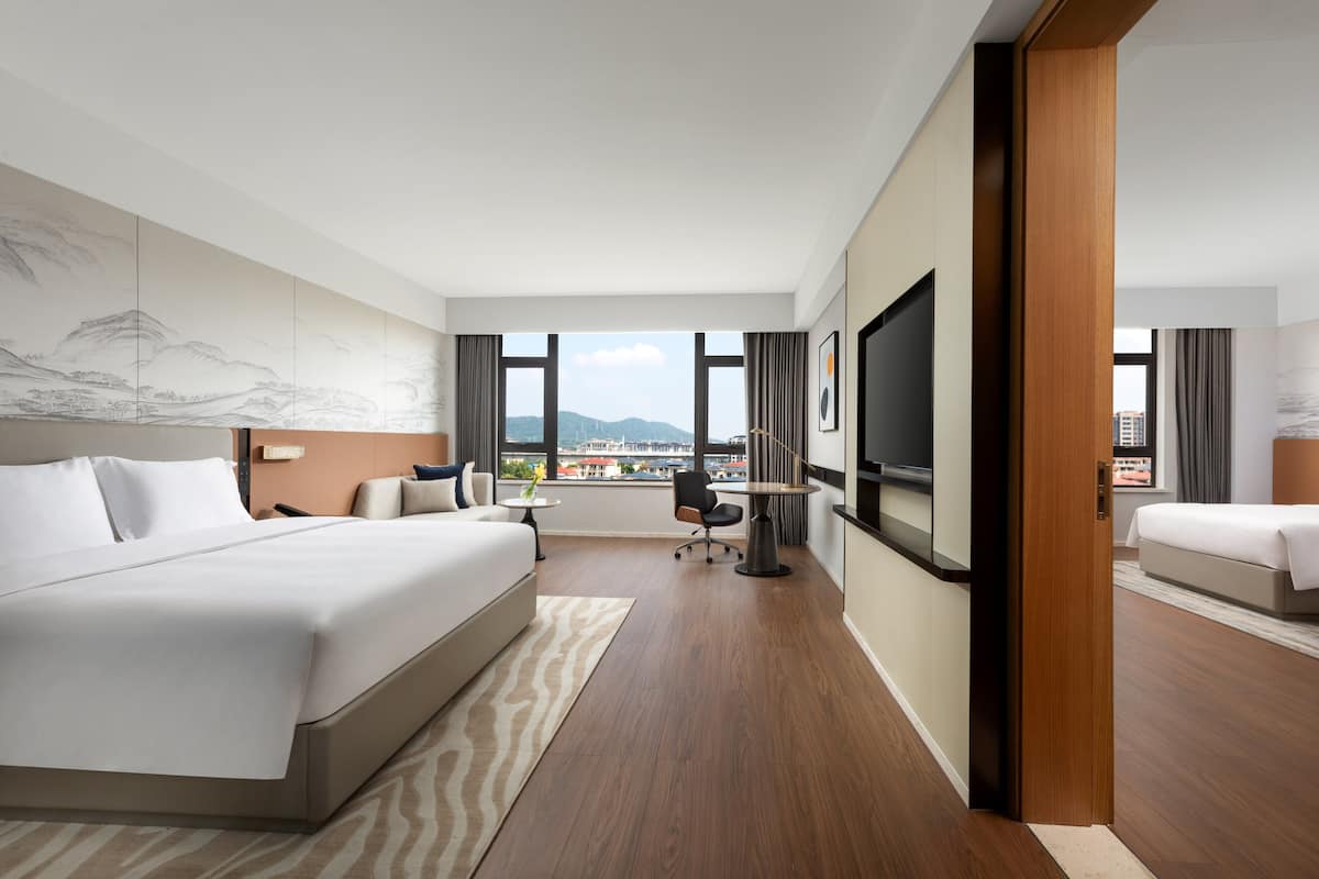 Une chambre d’hôtel avec un grand lit, un bureau, une chaise, une télévision et une vue sur le paysage urbain.