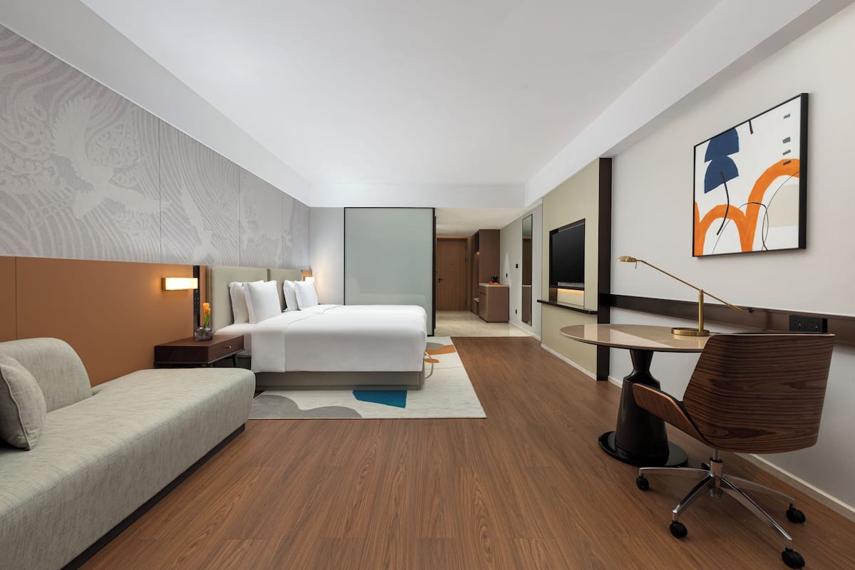 Une chambre d’hôtel moderne équipée d’un lit, d’un canapé, d’un bureau et d’une télévision.