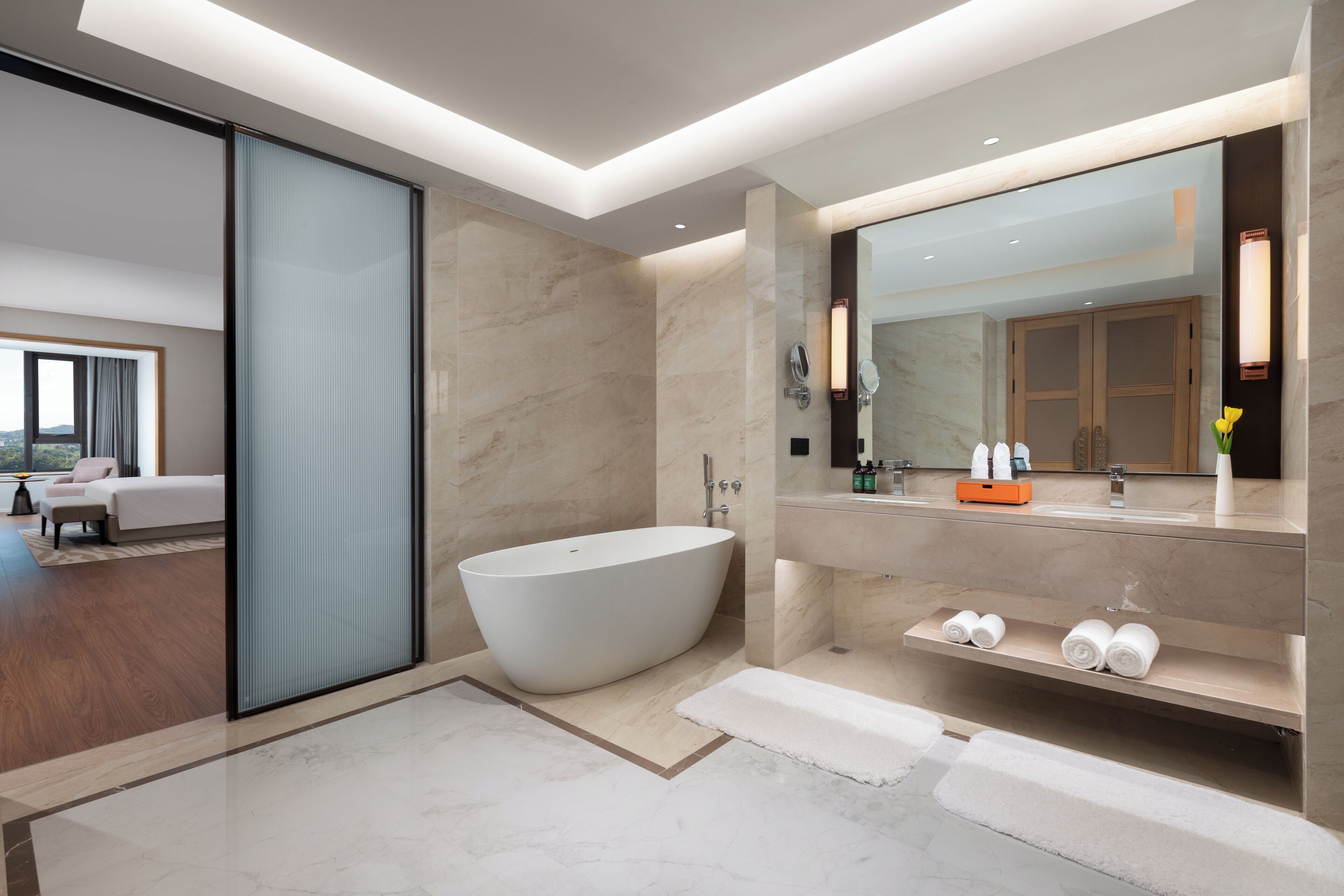 Un baño moderno con una bañera independiente, un espejo grande y un tocador con estantes.