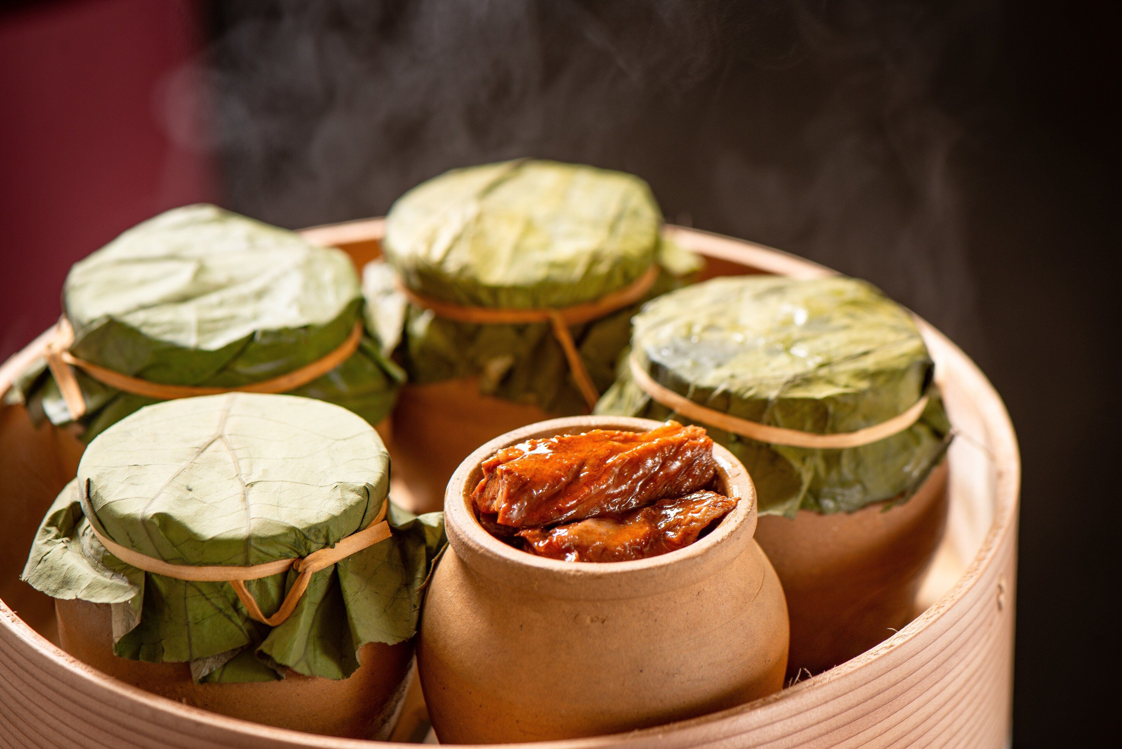 Una olla de barro tradicional con comida envuelta en hojas.