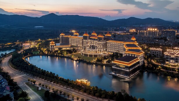 A hotel with multiple buildings, a large lake, and a mountain backdrop. - Crowne Plaza Xiangyang Fuchun Lakeside by IHG (Xiangyang)