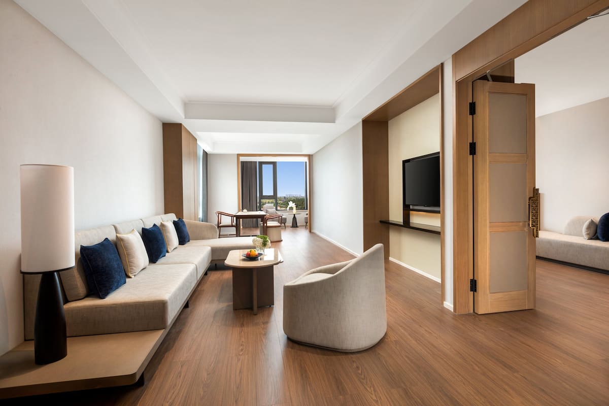 Une chambre d’hôtel moderne équipée d’un canapé, d’un fauteuil, d’une table à manger et d’un téléviseur.