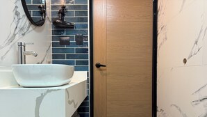 A bathroom with a white sink, a mirror, a towel rack, and a wooden door.