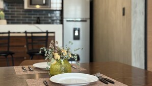 A dining table with a vase of dried flowers, plates, and cutlery.