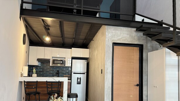 A modern kitchen with a microwave, refrigerator, and wooden dining table set for two.