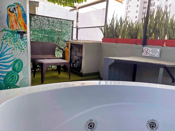 A hot tub with a metal frame, a chair, and a cactus painting on the wall.