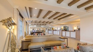 Un vaste espace de vie avec un long banc, une cuisine à l’arrière-plan et un design moderne au niveau du plafond.