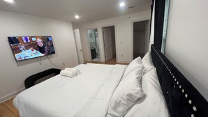 Une chambre d’hôtel avec un lit, un téléviseur fixé au mur et une porte donnant sur une salle de bain.