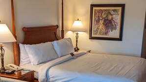 Une chambre d’hôtel comprenant un lit, des lampes de chevet, un bureau avec un téléphone, une chaise et une petite table.