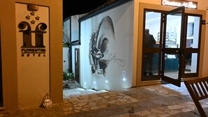 A hotel entrance with a large mural of a face, a sign for "Florentin Hotel," and a bench outside. - PALAZZO FIORENTINI CHARME HOTEL (Cariati)