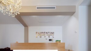 Una recepción de hotel con diseño moderno, un candelabro y un letrero que dice 'Fiorentini Hotel'.