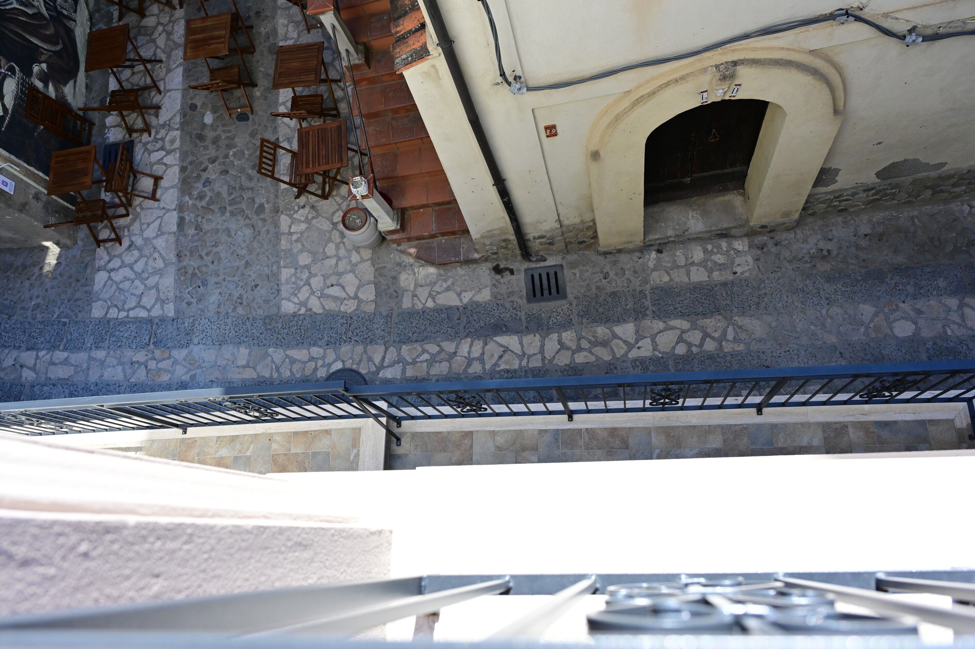 Ein gepflasterter Innenhof mit Außenbestuhlung und einem Metallgeländer.