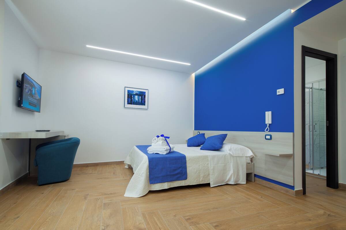 A modern hotel room with a bed, a desk, and a chair.