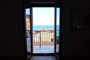 Eine geöffnete Tür, die auf einen Balkon mit Meerblick führt.