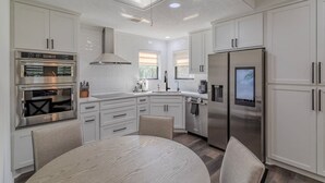 A modern kitchen with white cabinetry, stainless steel appliances, and a round dining table.