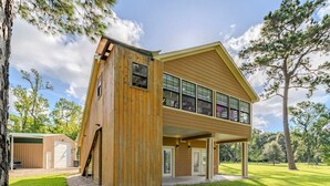 A two-story house with a large windowed upper floor and a smaller garage attached to the main structure.