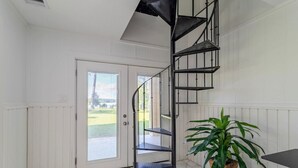 A spiral staircase in a room with white walls and a door leading outside.