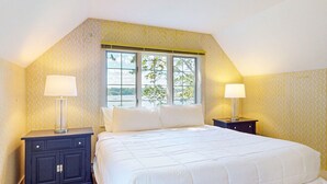 Ein Schlafzimmer mit einem großen Bett, zwei Nachttischen, einem Fenster mit Blick ins Freie und strukturierter Tapete.