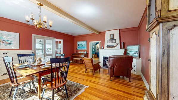 A dining area with wooden furniture, a chandelier, and a fireplace. - Oceanfront Retreat with Dock, Boothbay Harbor (Boothbay Harbor)