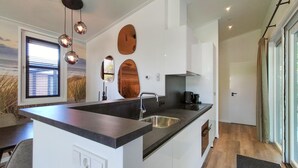 A modern kitchen with a central island, stainless steel sink, and pendant lighting.