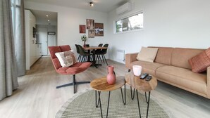 A modern living room with a sofa, a red armchair, a dining table, and a coffee table. - Pet friendly home in Hellendoorn with sauna (Hellendoorn)