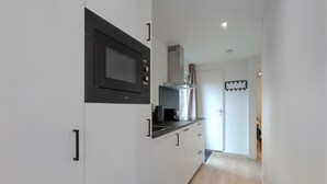 A narrow kitchen with white cabinets, a microwave, a coffee maker, and a stainless steel range hood. - Pet friendly home in Hellendoorn with sauna (Hellendoorn)