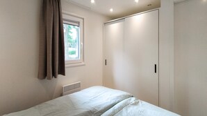 A bedroom with a bed, a window with curtains, a radiator, and a wardrobe. - Pet friendly home in Hellendoorn with sauna (Hellendoorn)