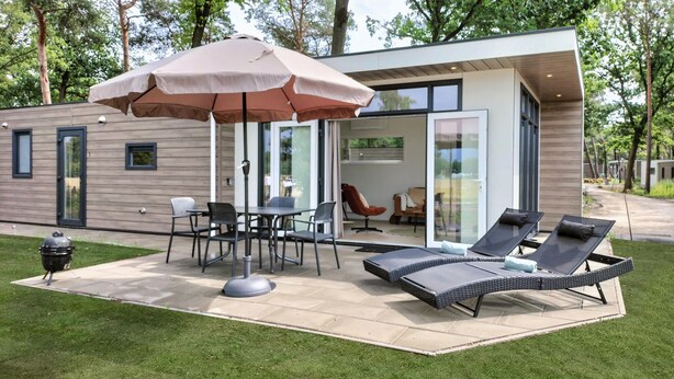 A modern outdoor patio with a table and chairs, a grill, and lounge chairs. - Pet friendly home in Hellendoorn with sauna (Hellendoorn)