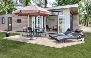 A modern outdoor patio with a table and chairs, a grill, and lounge chairs. - Pet friendly home in Hellendoorn with sauna (Hellendoorn)