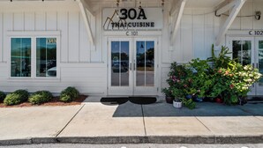 Un restaurant de cuisine thaïlandaise à la façade blanche, avec une enseigne indiquant « Cuisine thaïlandaise 30A » et le numéro « C 101 » au-dessus de l’entrée.