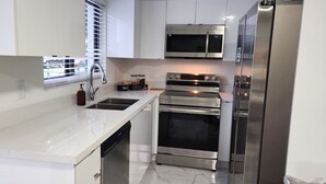 A modern kitchen with white cabinetry, a stainless steel microwave, oven, and refrigerator.