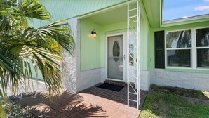 A house with a green exterior, a white door, and a small porch with a black mat. - Private Oasis with Pool and Tiki Bar (Largo)
