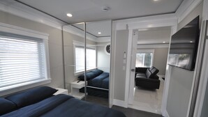 A modern bedroom with a large bed, a bedside table, a mirror, and a wardrobe.