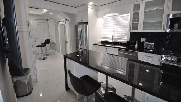 A modern kitchen with a black countertop, stainless steel appliances, and white cabinetry.