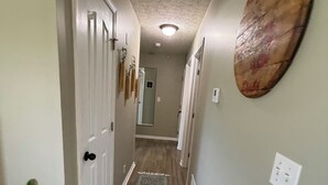 Un pasillo con piso de madera, un tapete estampado y una obra de arte colgada en la pared.