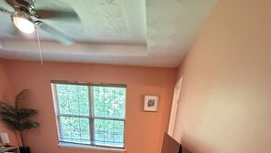 Une chambre à coucher avec un lit, un banc, une télévision et des plantes en pot.