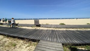 A wooden boardwalk leading to a sandy beach with clear skies.