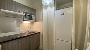 A compact kitchen with a microwave, sink, and a refrigerator.