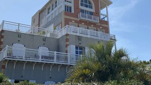 A multi-story building with a prominent corner balcony, a flat roof, and a brick facade.