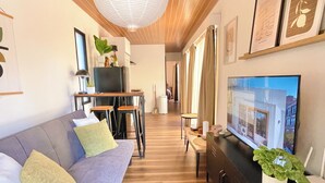 Een moderne woonkamer met een bank, televisie en houten plafond.