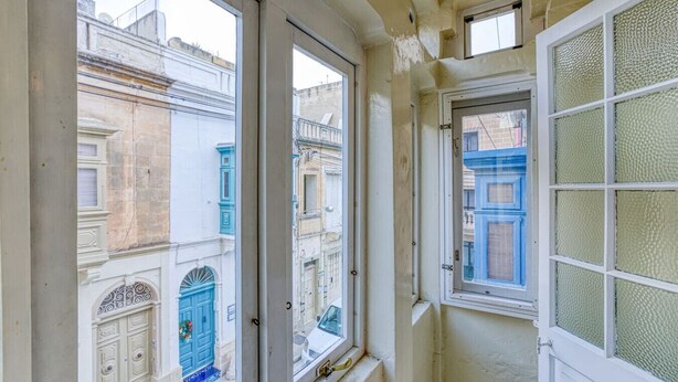 Un passadís estret amb tres finestres que donen a un carrer amb edificis antics.