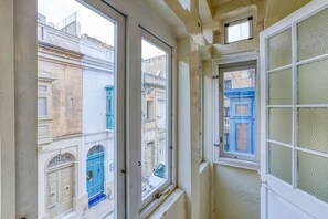 Un couloir étroit doté de trois fenêtres donnant sur une rue bordée de bâtiments historiques.