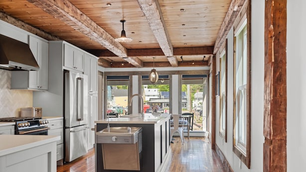 A modern kitchen with stainless steel appliances, a central island, and a wooden ceiling. - Quintessential Vermont Charm in the Heart of Stowe Village (Stowe)