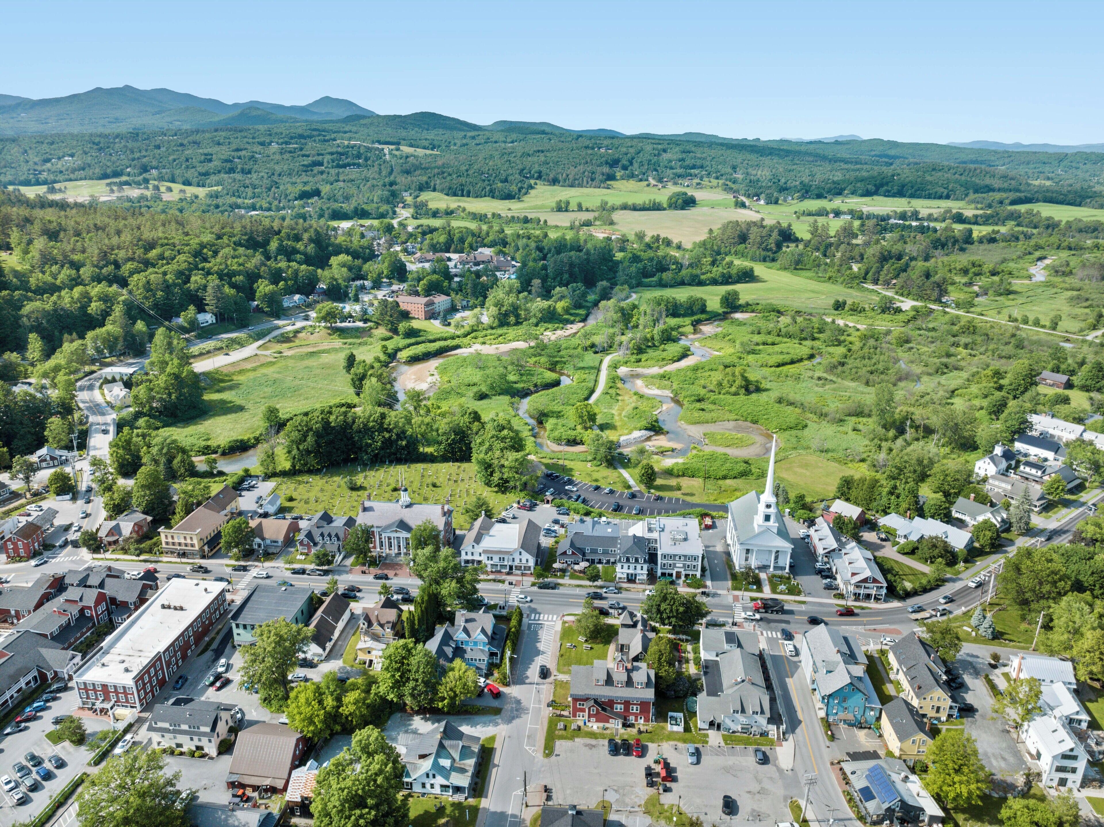 An aerial view of a town with a central church, surrounded by residential areas and green fields.