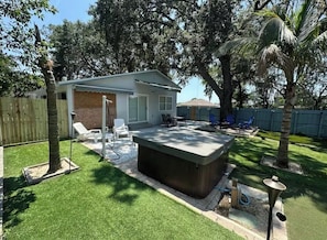 A backyard with a hot tub, patio furniture, and a wooden fence.