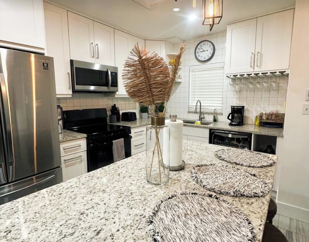 A modern kitchen with white cabinets, stainless steel appliances, and a central island with decorative rugs.